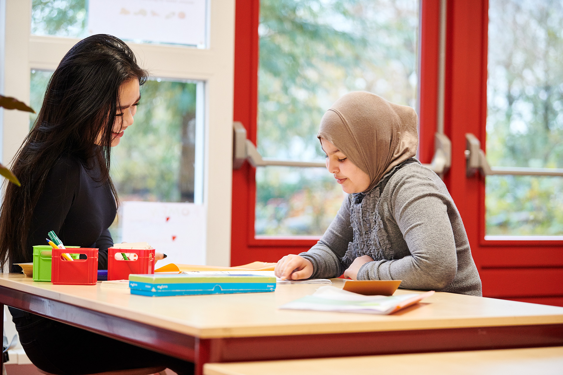 Leerkracht legt iets uit aan leerling