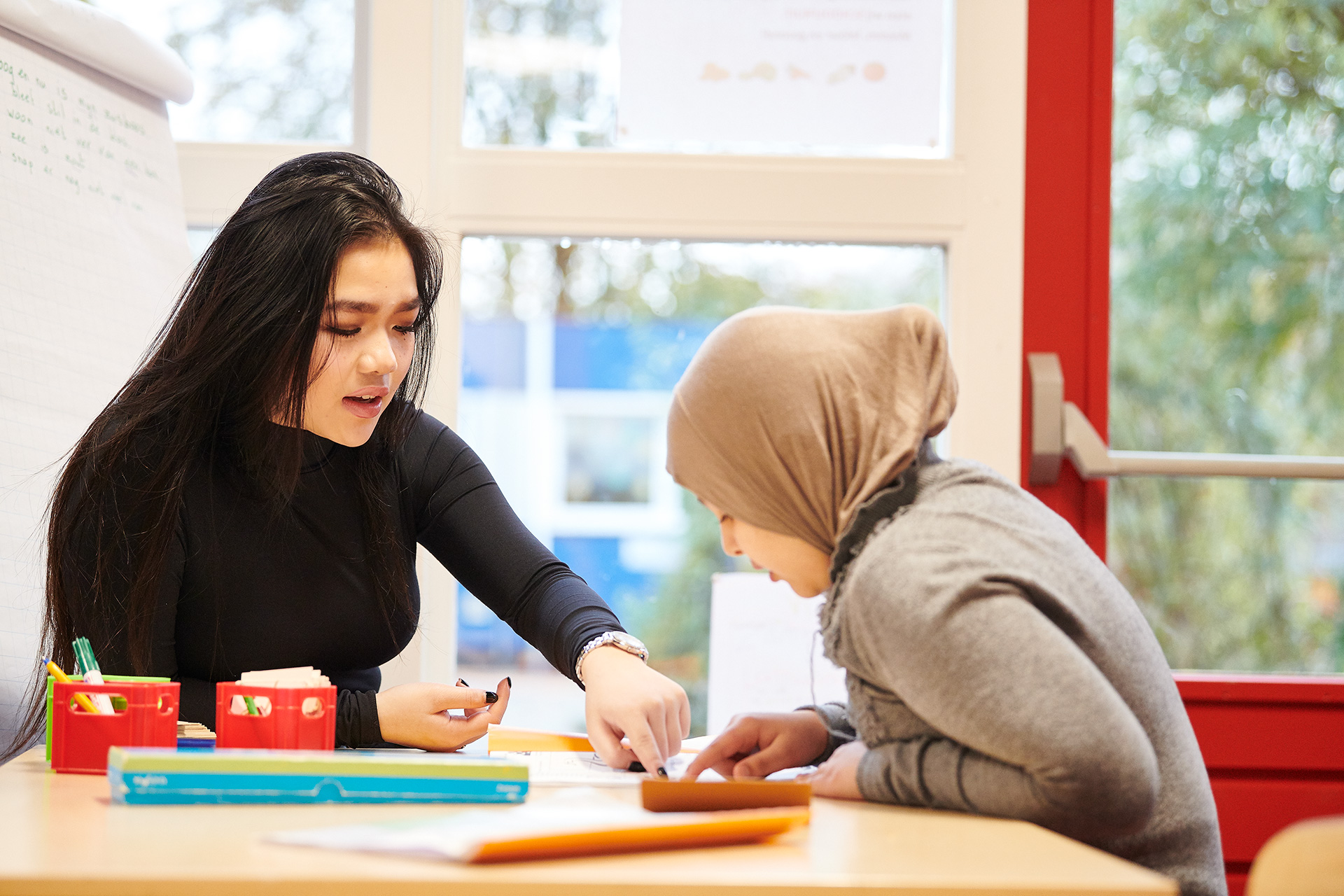 Leerkracht legt iets uit aan leerling