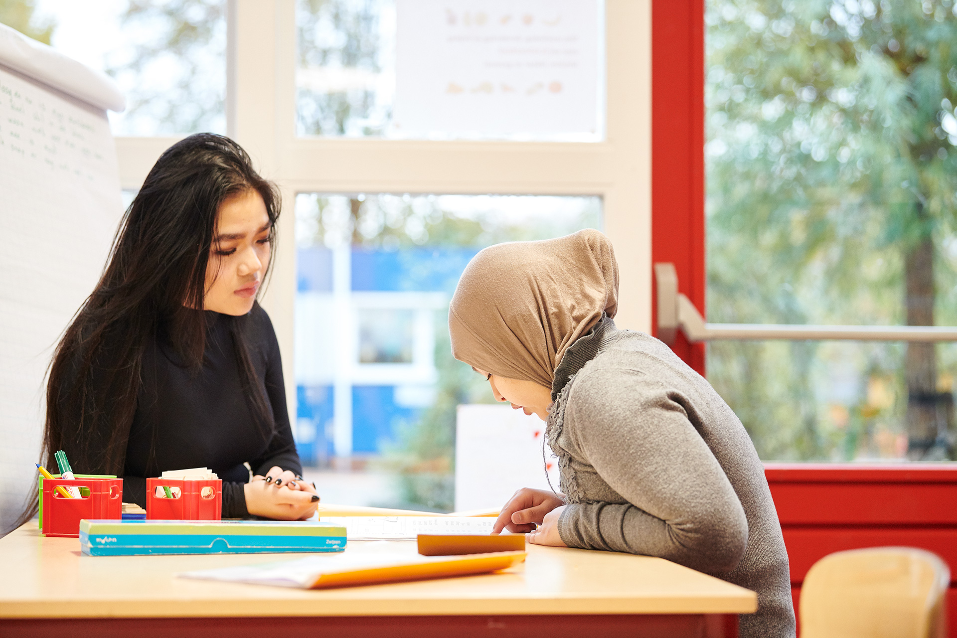 Leerkracht legt iets uit aan leerling