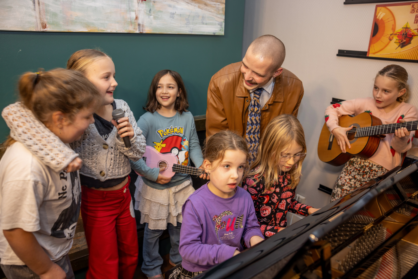 Kinderen met medewerker achter piano